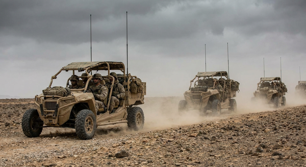Military light tactical utility vehicles navigating rugged terrain during a field exercise